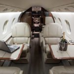 Interior of a Jet with a laptop and champagne on the tables.